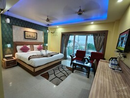 A hotel room with a bed, a desk, a chair, a TV, and a window with a view.