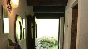 Un couloir avec un plafond en bois, un tapis et une porte donnant sur l’extérieur.
