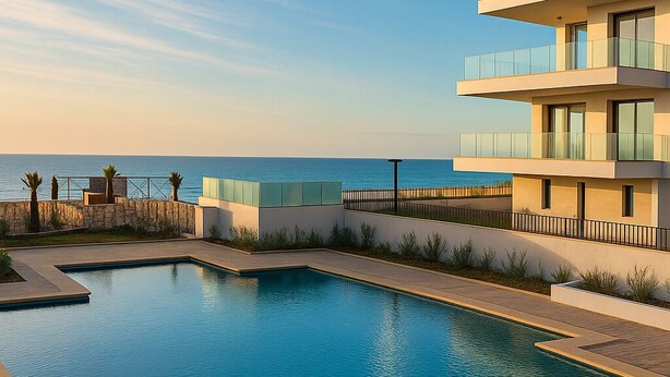 Um hotel moderno com piscina, vista para o mar e um edifício de vários andares com varandas.