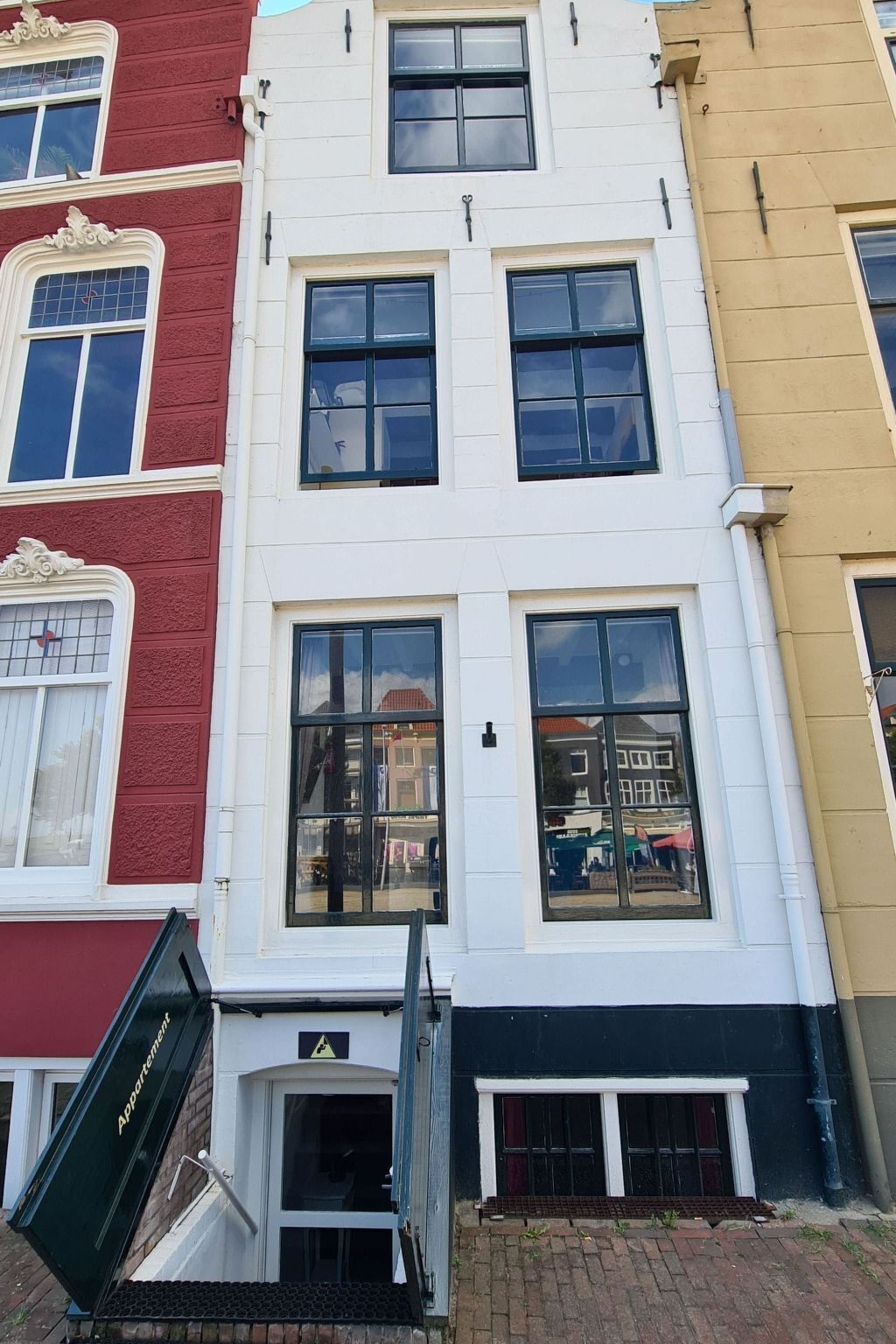 Ein mehrstöckiges Gebäude mit weißer Fassade und großen Fenstern.