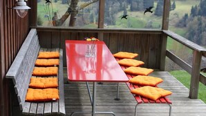 A wooden deck with a red table and benches, overlooking a grassy landscape.