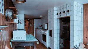 A kitchen with white tiled walls, a wooden table, and a brick floor.