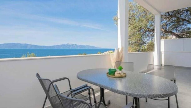 A covered outdoor seating area with a table and chairs, overlooking a scenic view of the sea and mountains. - Wohnung mit tollem Meerblick und 2 Bädern by Interhome (Podaca)