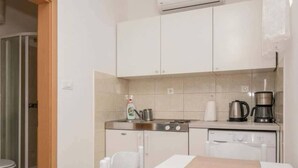 A compact kitchen with white cabinets, a gas stove, a coffee maker, and a dishwasher. - Wohnung mit tollem Meerblick und 2 Bädern by Interhome (Podaca)