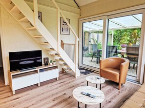 A modern living room with a TV, a sofa, a coffee table, and a staircase leading to a balcony. - Buurtweg 75 by Interhome (Stavenisse)