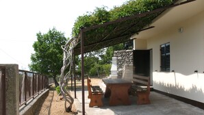 En terrasse med pergola, udendørs møbler og en stenvæg.