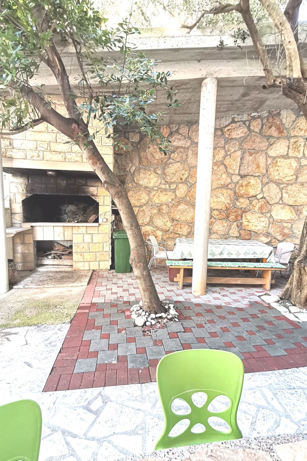 A stone wall with a fireplace, a bench, and a green chair.