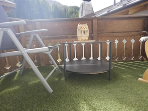 A wooden deck with a metal table and chairs, surrounded by a white picket fence.