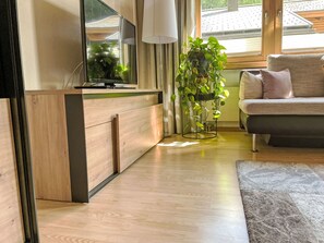 A modern living room with a wooden cabinet, a flat-screen TV, a potted plant, and a sofa with cushions. - Kleinstein-Maass by Interhome (Samnaun)