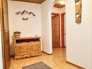 A hallway with wooden cabinets, a rug, and a wall with a mountain silhouette and the word 'Glück'. - Kleinstein-Maass by Interhome (Samnaun)
