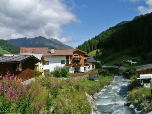 A mountain cabin with a wooden exterior, a balcony, and a view of a flowing river.