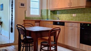 Una cocina con armarios de madera, una mesa de comedor con sillas, una ventana y un lavavajillas.