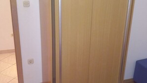 Ein Zimmer mit einem Holzschrank, einem blauen Bett und einem Fliesenboden.