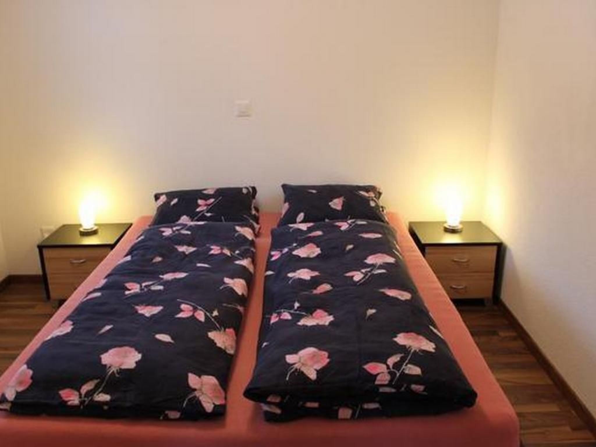 A twin bed with a floral bedspread and two bedside lamps.