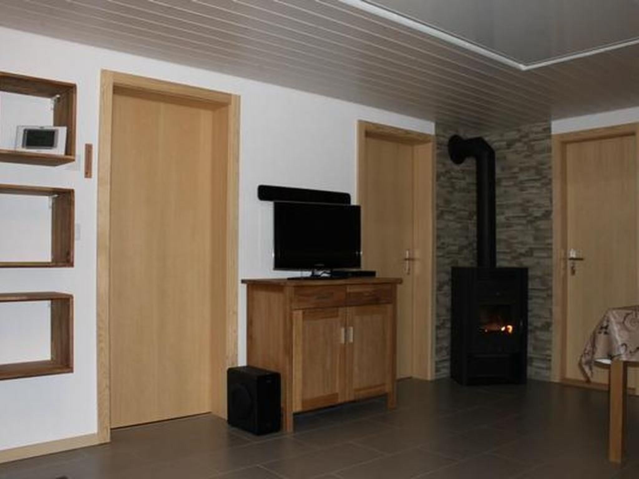 A living room with a television on a wooden cabinet, a fireplace, and a small speaker.