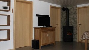 A living room with a television on a wooden cabinet, a fireplace, and a small speaker. - Adlerhorst by Interhome (Rosswald)