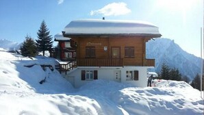 A wooden chalet with a balcony, surrounded by snow-covered mountains. - Adlerhorst by Interhome (Rosswald)