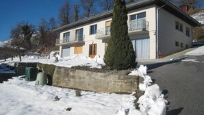 Un bâtiment à deux étages doté d’un balcon au deuxième étage, d’une porte de garage et d’un sol recouvert de neige.