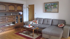 Un salon avec un canapé gris, un meuble en bois et un tableau accroché au mur.