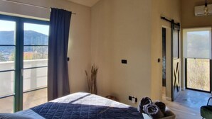 Ein Schlafzimmer mit einem großen Bett, Blick ins Freie und einer Deckenleuchte.