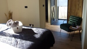 Ein Schlafzimmer mit Bett, Stuhl, Fenster und Blick ins Freie.