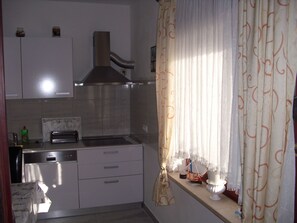 Een koelkast, een oven, een vaatwasser, kookgerei, borden en bestek