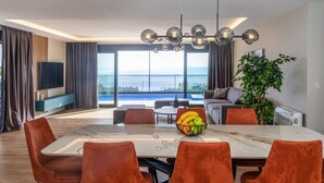 A modern dining area with a large table, orange chairs, and a fruit bowl. - Villa Mario by Interhome (Bast)