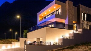 A modern multi-story building with balconies and large windows, set against a mountainous backdrop. - Villa Mario by Interhome (Bast)