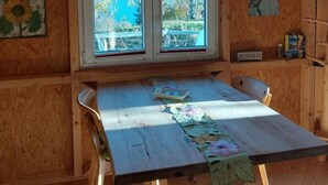 A wooden interior with a table, two windows, and a ceiling light.