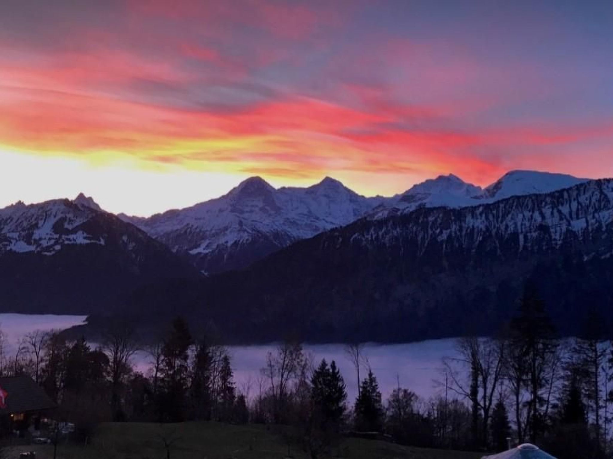 Paesaggio montano con cime innevate e un lago in primo piano.