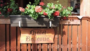 Een houten bordje met de tekst 'Chalet Bellevue', bevestigd aan een houten hek.