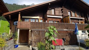 Eine Holzchalet mit Balkon, einem Holzzaun und einem roten Handtuch, das an der Reling hängt.