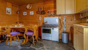 Una cocina rústica con paredes de madera, suelo de piedra, estufa y armarios de madera.