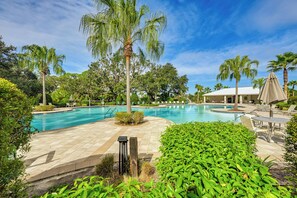 Una piscina circondata da palme e lettini.