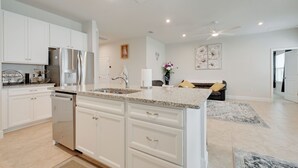 Una cocina moderna con armarios blancos, un refrigerador de acero inoxidable y una encimera de granito.