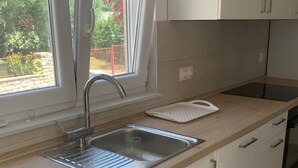 Una cucina moderna con lavello in acciaio inossidabile, piano di lavoro in legno e mobili bianchi.