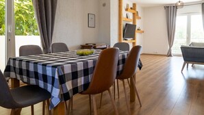 Uma sala de jantar com toalha de mesa xadrez, cadeiras de madeira e luminária pendente.