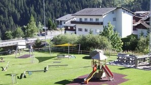 A playground with slides and swings, surrounded by a grassy area and a building in the background. - Fontauna Degonda by Interhome (Sedrun)
