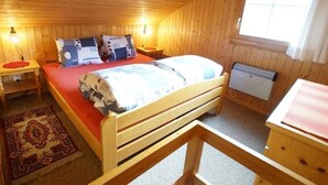 A cozy wooden cabin bedroom with a bed, nightstands, a heater, and a window. - Fontauna Degonda by Interhome (Sedrun)