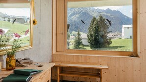Un bureau en bois donnant sur un paysage de montagnes et sur des oiseaux qui volent à l’extérieur.
