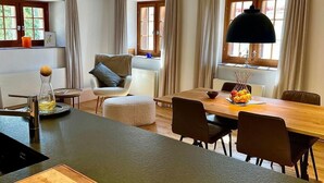 Una cocina moderna con una isla de madera, una mesa de comedor con sillas e iluminación colgante.