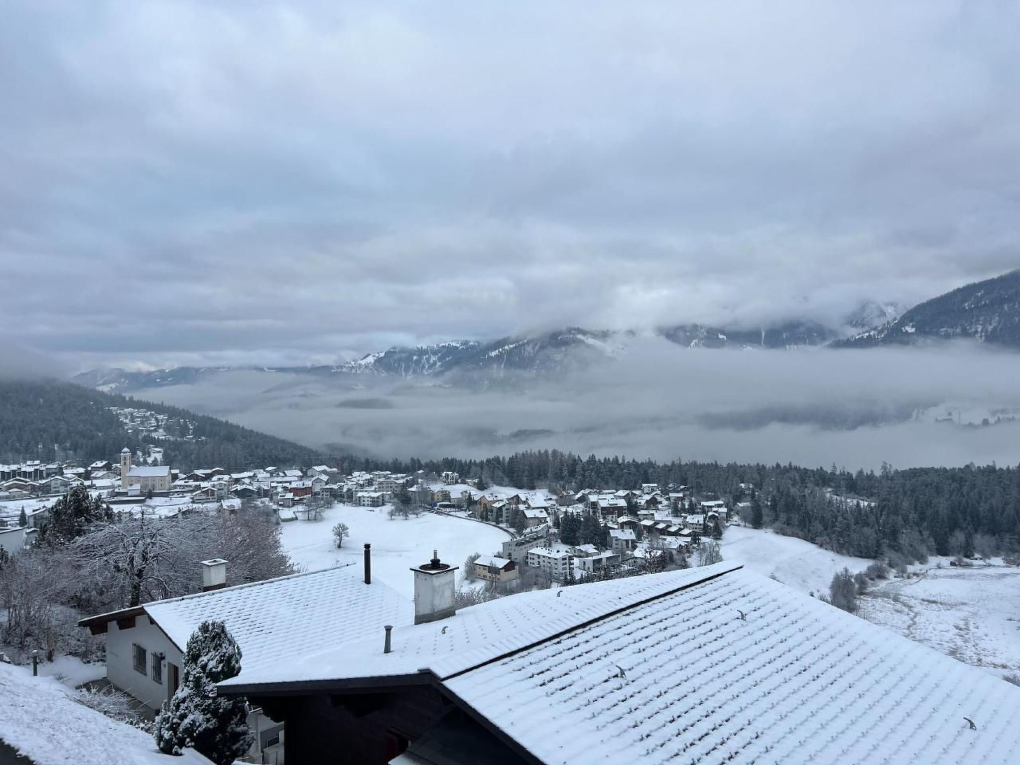 A snow-covered town with buildings and a mountain backdrop.