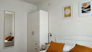 Una camera da letto con un letto, un'armadio bianco, un comodino e due opere d'arte incorniciate appese al muro.