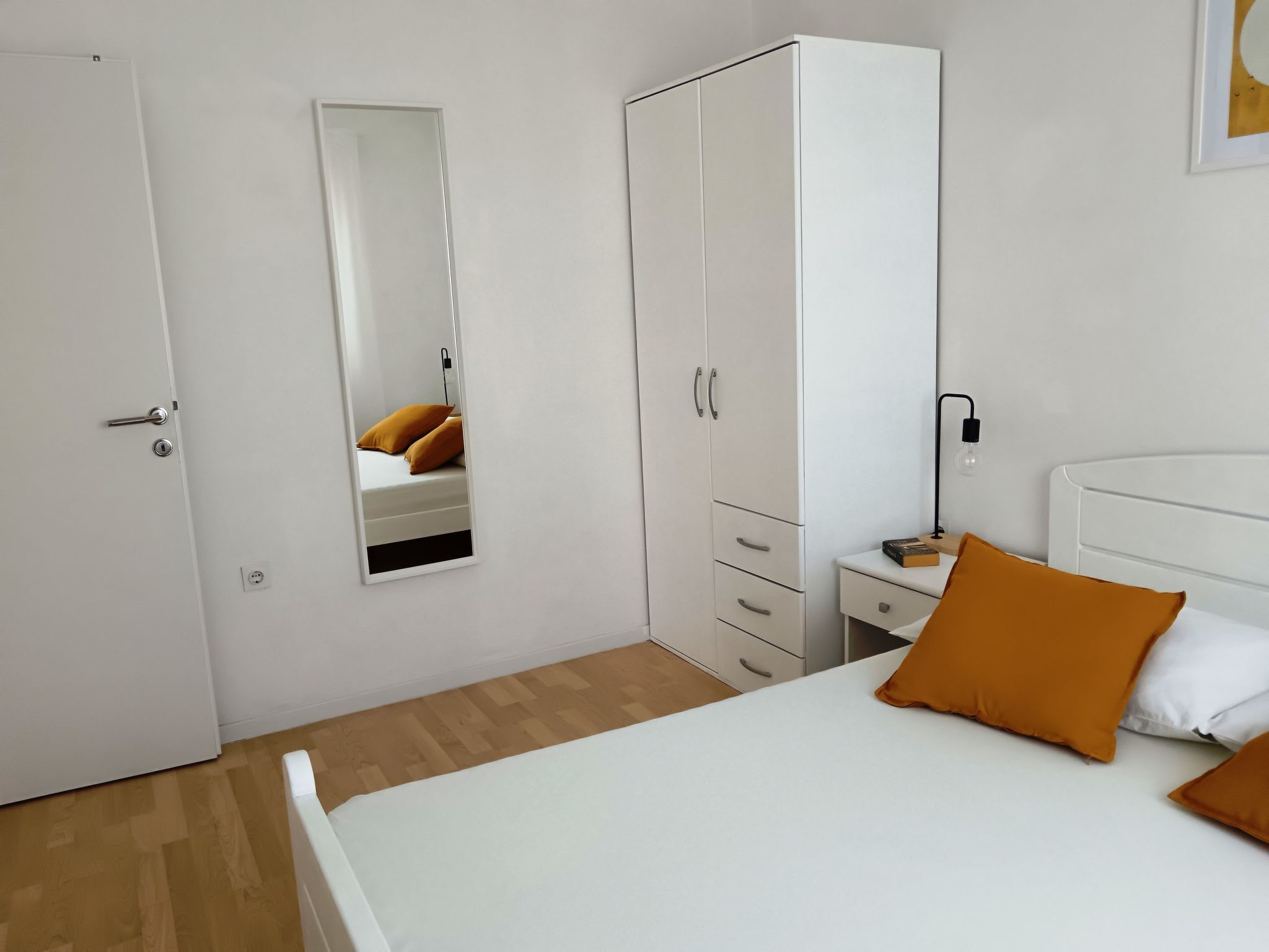 Een slaapkamer met een bed, een garderobe, een nachtkastje en een nachttafeltje.