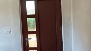 Una stanza con una porta marrone, un condizionatore sopra e un pavimento piastrellato.