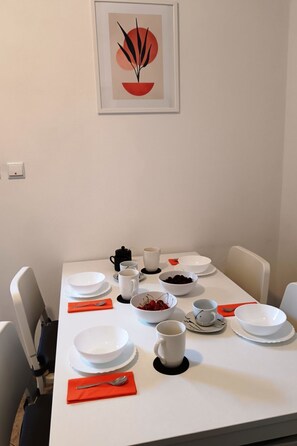 A dining table set with white plates, bowls, and cups, accompanied by red napkins and a spoon. - "Appartement "Ana"" by Interhome (Brač/Povlja)