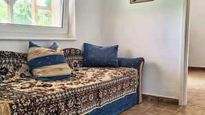 A room with a sofa bed, patterned bedspread, and a window with a view of greenery. - Apartment am See by Interhome (Balatonmariafurdo)