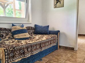 A room with a sofa bed, patterned bedspread, and a window with a view of greenery. - Apartment am See by Interhome (Balatonmariafurdo)