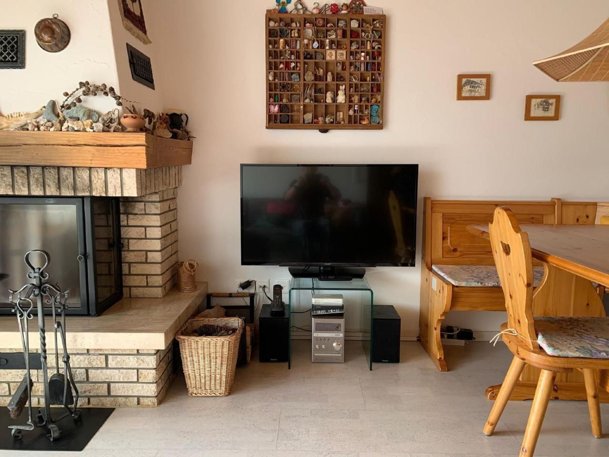 Una sala de estar acogedora con chimenea, televisor, una mesa de comedor de madera y un mueble con varios objetos.