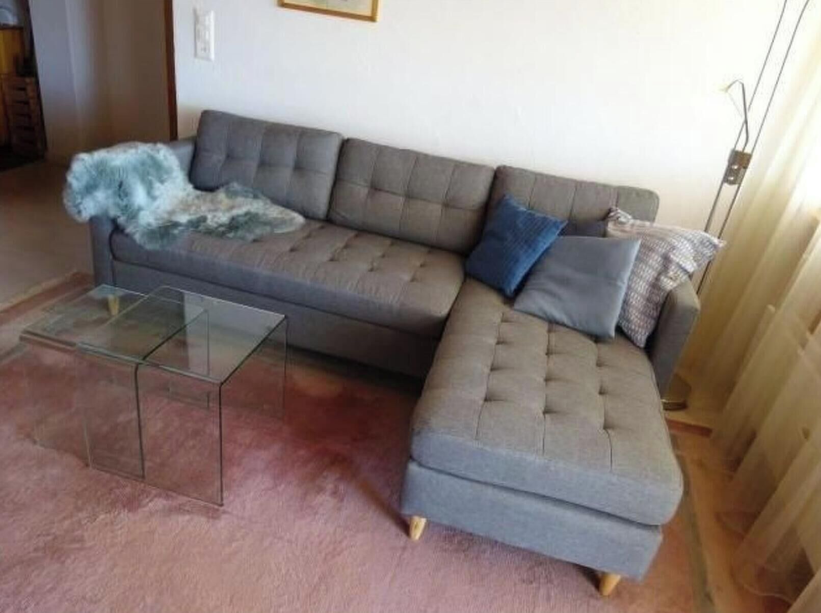 A grey sectional sofa with a glass coffee table in a living room.